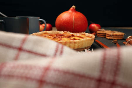 Tart pie and pumpkin on dark black surface