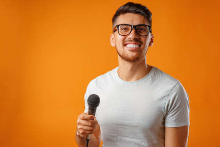 Hispanic young handsome man singing with joy in microphoneの写真素材