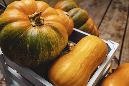 Pile of pumpkins in wooden box on wooden board
