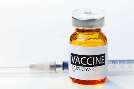 Sars-cov-2 vaccine vial and syringe on white tableの写真素材