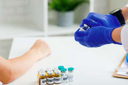 Hand of a doctor taking vial with sars-cov-2 vaccine