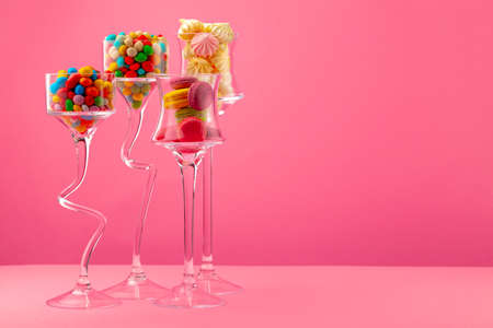 Glass containers with candies against pink backgroundの写真素材