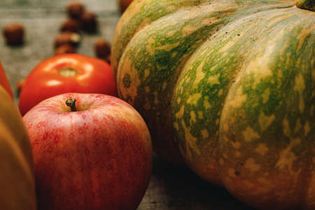 Pile of red apples and pumpkins on wooden surfaceの写真素材