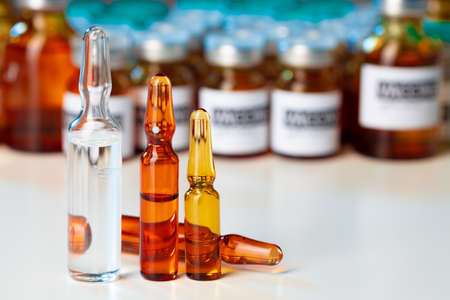 Pile of glass medical vials with medication on lab table