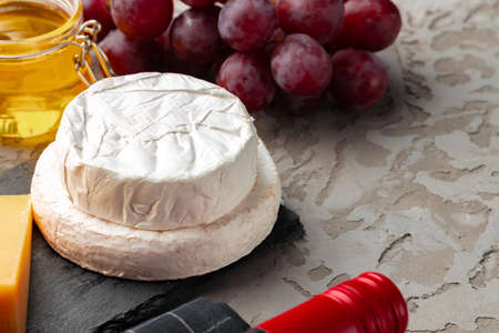 Cheese served with grapes and honey on grey surfaceの写真素材