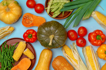 Variety of vegetables including pumpkins on blue pastel background