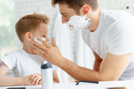 Father teaches his little son how to shave faceの写真素材