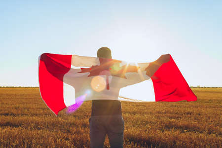 Man with a flag of Canada standing in fieldの写真素材
