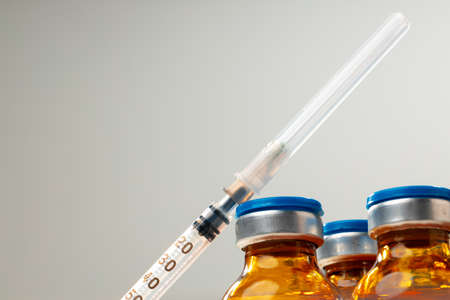 Medication vaccine vials and syringe on white background