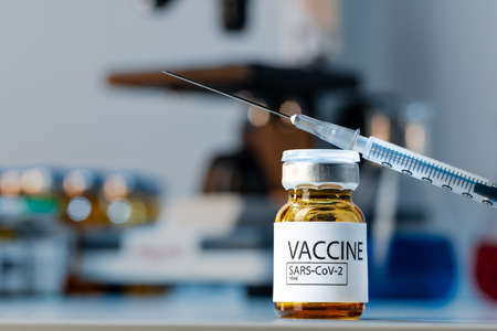 Covid-19 vaccine bottle with a syringe on lab tableの写真素材
