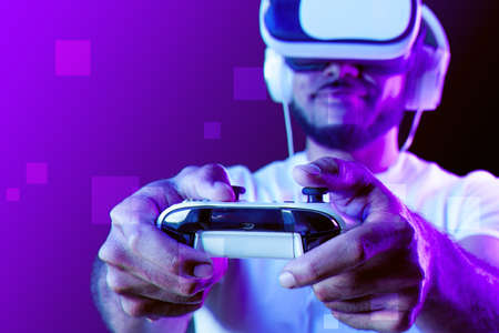 Afro american man wearing VR glasses in neon light against purple background