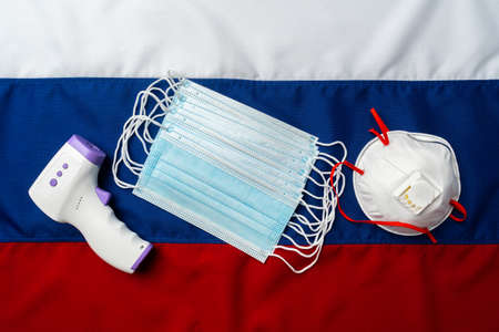 Medical face masks and thermometer on flag of Russiaの写真素材