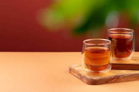 Two glass cups of black tea on beige tableの写真素材