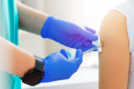 Doctor hands making a vaccination in the shoulder of patient