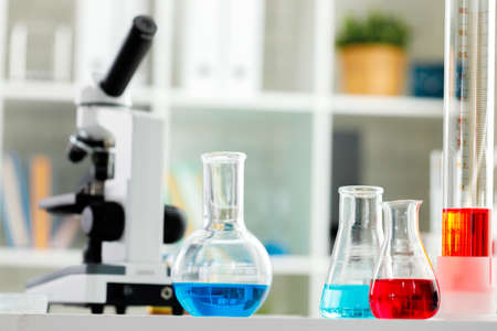 Microscope on the table with glassware in laboratory