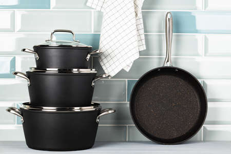 New black cookware against blue tile wall