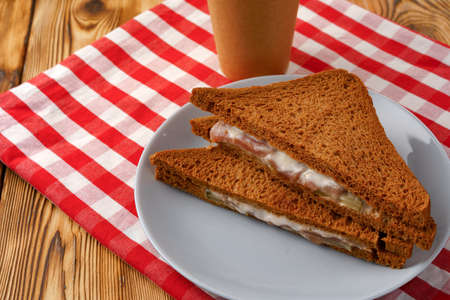 Toast sandwich and cup of coffee on napkin on wooden tableの写真素材