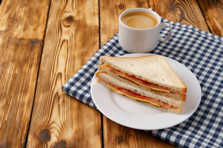 Toast sandwich and cup of coffee on napkin on wooden tableの写真素材