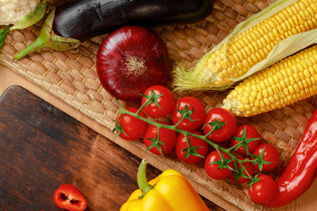 Cherry tomatoes, corn and onion on wooden tableの写真素材