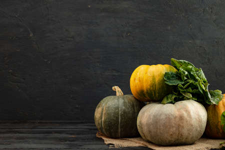 Stacked green pumpkins and greens on dark background