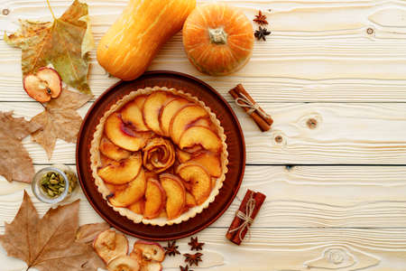 Apple tart pie on table with pumpkin and dry leavesの写真素材