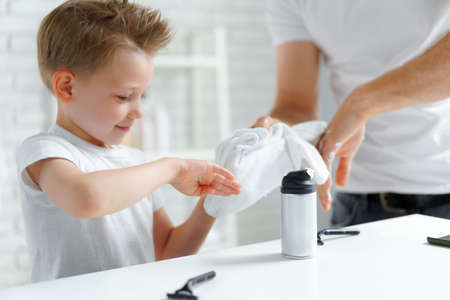 Little boy and father wiping hands of shawing foam with towelの写真素材