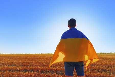 Man with a flag of Ukraine standing in field