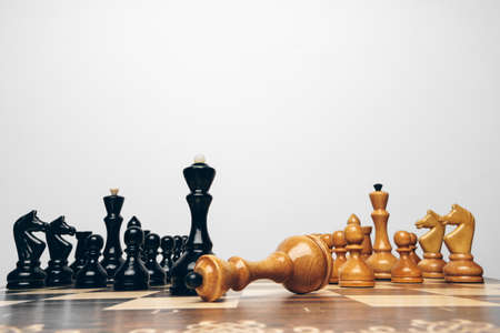 Chessboard with wooden figures against grey background