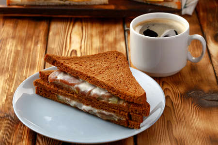 Toast sandwich and cup of coffee on napkin on wooden tableの写真素材