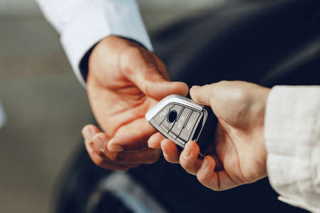 Car salesperson giving keys to a client close upの写真素材
