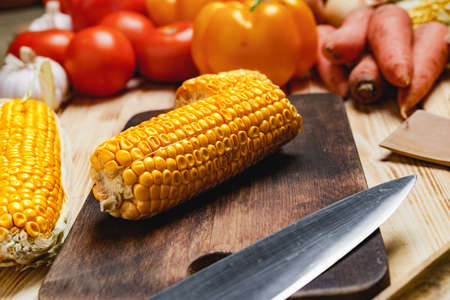 Cobs of corn on wooden cutting boardの写真素材