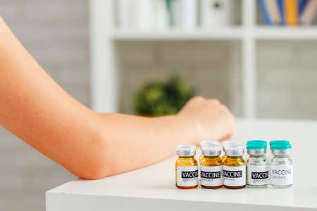 Vaccine bottles and patient waiting for vaccination
