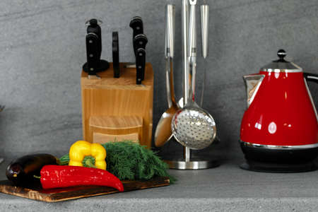 Kitchenware and cutting board with vegetables on countertopの写真素材