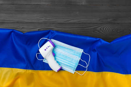Medical mask and contactless thermometer on the flag of Ukraine