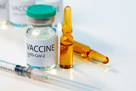 Sars-cov-2 vaccine vial and syringe on white table