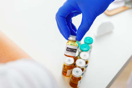 Hand of a doctor taking vial with sars-cov-2 vaccine