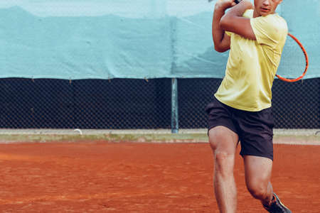 Young handsome man playing tennis on the tennis court