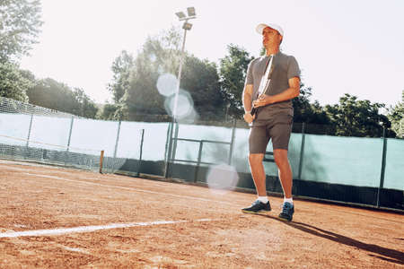 Middle-aged man playing tennis on outdoor tennis filedの写真素材