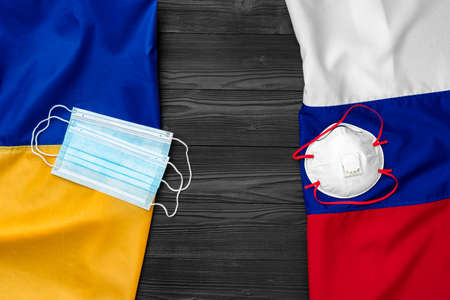 Flags of Russia and Ukraine on wooden background with medical masksの写真素材