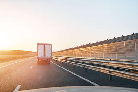 Truck driving on highway road at sunrise