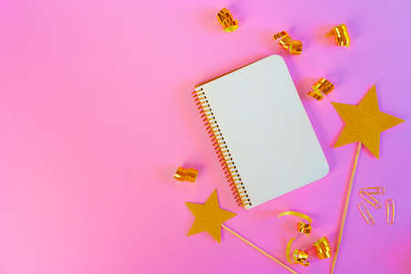 Notepad paper with golden ribbons and gold stars on pink background