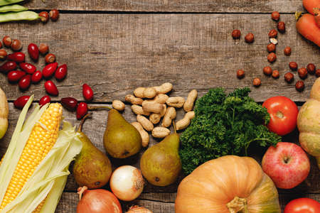 Top view of vegetables, dogwood and nuts on wooden tableの写真素材