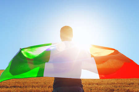 Man with a flag of Italy standing in fieldの写真素材
