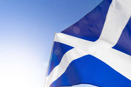 Flag of Scotland waving against blue skyの写真素材