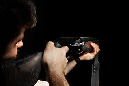 Unrecognizable man aiming with a hunting rifle in darkの写真素材