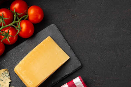 Cherry tomatoes and piece of cheese on black tableの写真素材