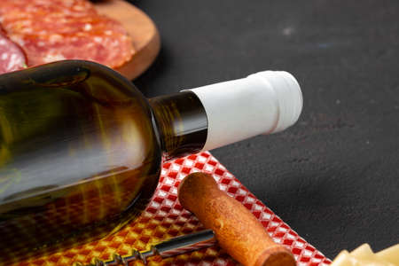Bottle of white wine and meat slicing on black surface close upの写真素材