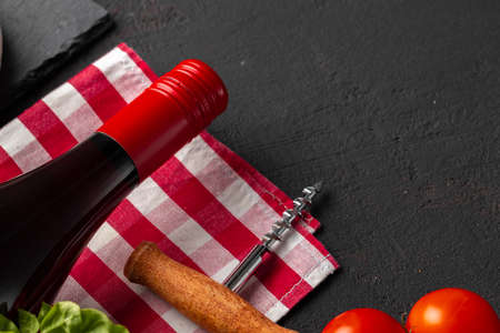Wine bottle with cork screw and cherry tomatoes on black backgroundの写真素材