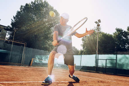 Middle-aged man playing tennis on outdoor tennis filed