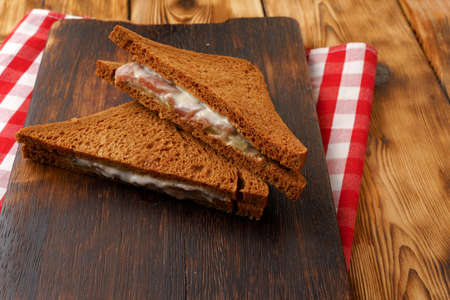 Toasted rye sandwich with ham cut into halves on tableの写真素材